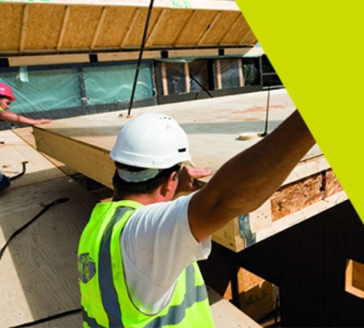 Construction site workers aiding the delivery of off-site timber panels 