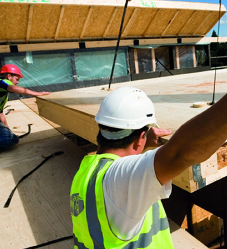Construction site workers aiding the delivery of off-site timber panels 